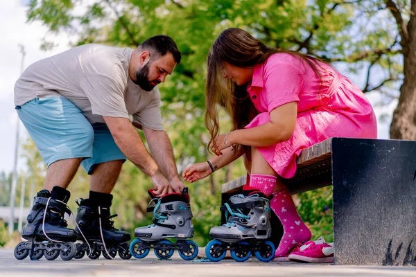 Young Couple Guy Helps Girl Put Rollerblades Who Sitting Bench — Stock Photo, Image