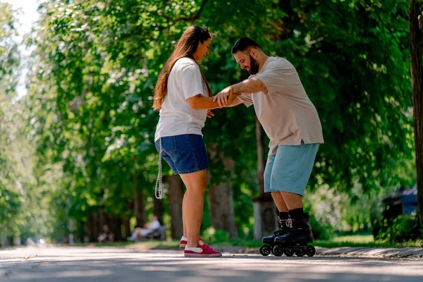 Young Couple Girl Holds Hands Guy Who Roller Skating Helps — Stock Photo, Image