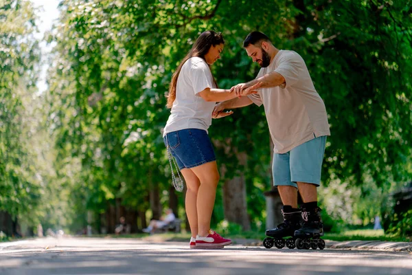 Young Couple Girl Holds Hands Guy Who Roller Skating Helps — Stock Photo, Image