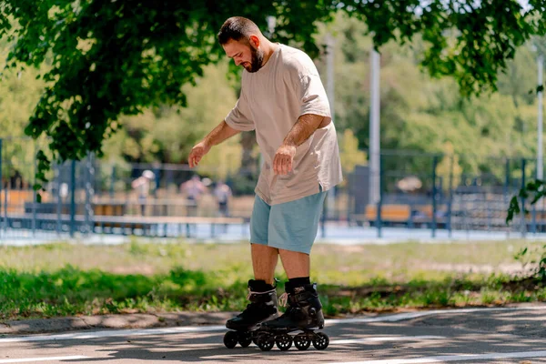 Young guy with beard learns to rollerblade in a city park concept of wanting to learn new things and body positivity
