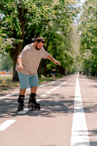 Young guy with beard learns to rollerblade in a city park concept of wanting to learn new things and body positivity