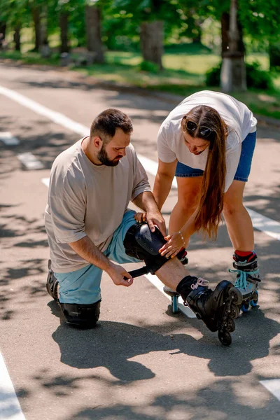 Young Couple Girl Helps Guy Put Kneepad While Rollerblading Park — Stock Photo, Image