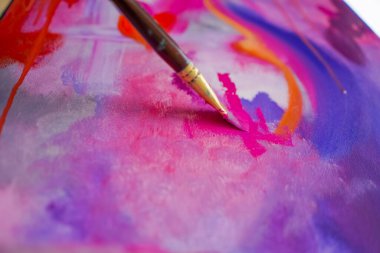 Bir resim stüdyosunun sehpasında duran bir ressama yağlı boya uygulayan bir fırçayla yakın plan bir resim.