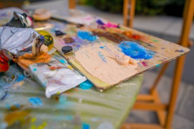 Üstlerinde boya kalıntıları olan boya paletleri ve güzel sanatlar kavramını resmetmek için stüdyoda yanlarındaki fırça.