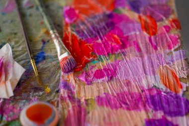 Üstlerinde boya kalıntıları olan boya paletleri ve güzel sanatlar kavramını resmetmek için stüdyoda yanlarındaki fırça.