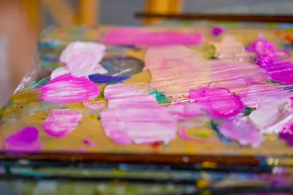 close-up of paint palettes with traces of oil paint on them and a brush lying next to them in studio for painting the concept of love of fine art