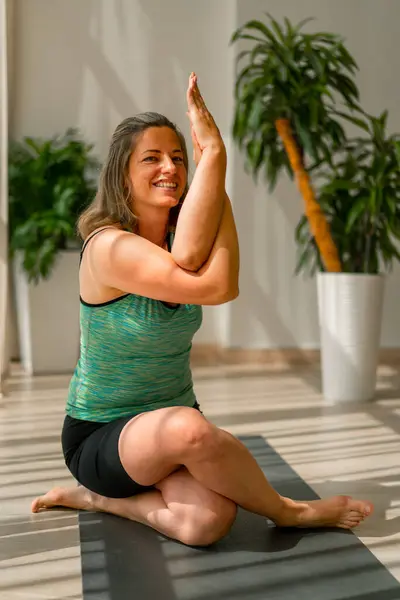 a plump smiling girl in a sports uniform crossed her arms for yoga exercise in  beautiful hall