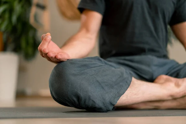 close-up of hands and fingers of man meditating in hall and sitting in lotus position man taking care  his mental health