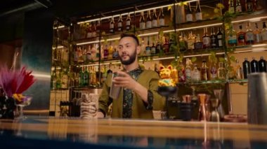 Profesyonel bir barmen elinde içkiyle hokkabazlık yapar. Bardaki bir kulüpte kokteyl yapma süreci.