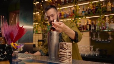 Profesyonel bir barmen, bardaki bir kulüpte kokteyl yapmak için bardağa alkol döker.