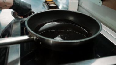 Bir restoranda profesyonel bir mutfakta şef tavada sulu tavuk filetosu pişiriyor.