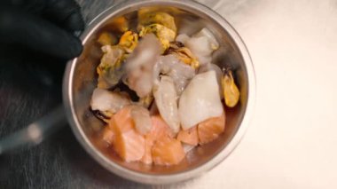 Profesyonel mutfakta yemek pişirmeden önce metal bir kasede taze çiğ deniz ürünleri.