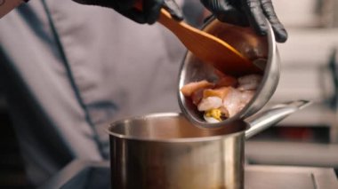 Profesyonel restoran aşçısı et suyuna deniz mahsulü ekliyor baharatlı çorba Tom yum asya yemeği yakın plan