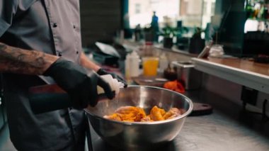 Yakın plan aşçı siyah eldiven giyip Asya mutfağında çiğ tavuk kanadı pişiriyor.