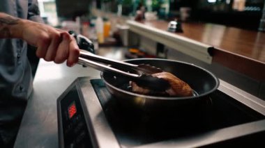 Sulu ördek göğsü, kızarmış deri ve tereyağlı tava. Aşçı eti kızartıyor.