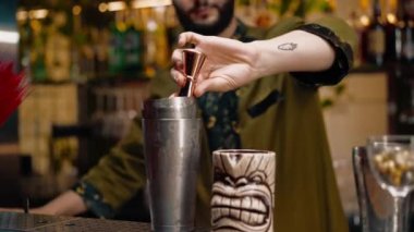 Profesyonel bir barmen ölçü kabına alkol döker. Barda yakın plan bir kulüpte kokteyl hazırlama süreci.