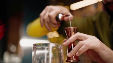 Profesyonel barmen bardaki ölçüm bardağına alkol döker.