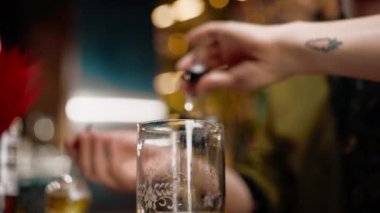Profesyonel barmen bardaki ölçüm bardağına alkol döker.