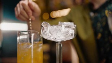 Klasik bir barmen, barda kokteyl hazırlamak için uzun bir kaşıkla uzun bir bardakta alkol karıştırır.