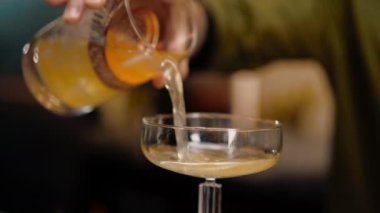 Deneyimli barmen kadehten cam bar restoranına taze alkollü kokteyl döker.
