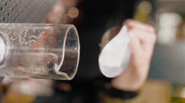Bir barmenin yakın çekimi kokteyl bardağına buz doldurur. Lezzetli kokteyller hazırlamak için.