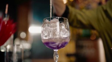 Profesyonel barmen bardaki ölçüm bardağına alkol döker.
