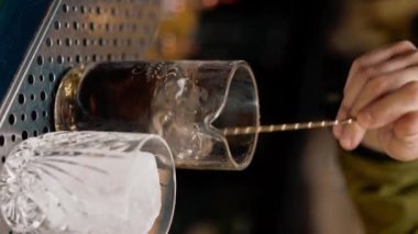 Profesyonel barmen bardaki ölçüm bardağına alkol döken bir kokteyl hazırlıyor.