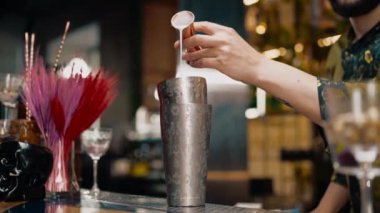 Profesyonel bir barmen, bardaki bir kulüpte kokteyl yapmak için bardağa alkol döker.