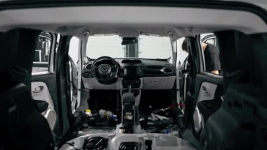 Detaylı işlemler sırasında araba yıkama işçisinin fırça ve araba kimyasalları kullanarak lüks bir arabanın gösterge tablosunu temizlemesi.