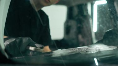 Detaylı işlemler sırasında araba yıkama işçisinin fırça ve araba kimyasalları kullanarak lüks bir arabanın gösterge tablosunu temizlemesi.