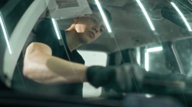 Detaylı işlemler sırasında araba yıkama işçisinin fırça ve araba kimyasalları kullanarak lüks bir arabanın gösterge tablosunu temizlemesi.