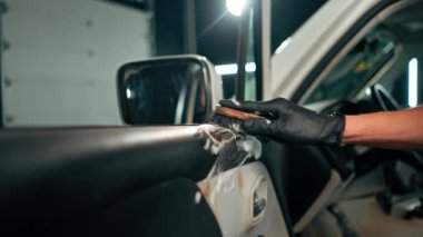 Detaylı işlemler sırasında lüks bir arabanın kapı kartını temizlerken plastik fırça kullanan bir oto yıkama işçisinin yakın çekimi.