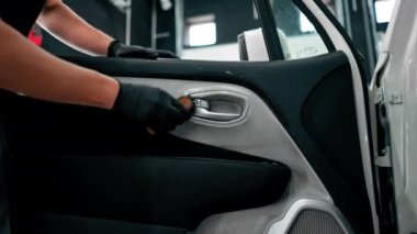 Detaylı işlemler sırasında lüks bir arabanın kapı kartını temizlerken plastik fırça kullanan bir oto yıkama işçisinin yakın çekimi.