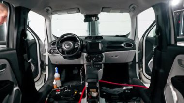 Detaylı işlemler sırasında araba yıkama işçisinin fırça ve araba kimyasalları kullanarak lüks bir arabanın gösterge tablosunu temizlemesi.