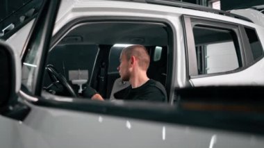 Detaylı işlemler sırasında araba yıkama işçisinin fırça ve araba kimyasalları kullanarak lüks bir arabanın gösterge tablosunu temizlemesi.