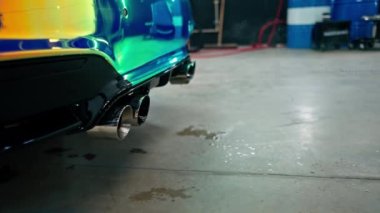 Egzoz borusuna yakın çekim bukalemun renkli lüks bir arabanın dumanını yayarak araba yıkama işlemi sırasında...