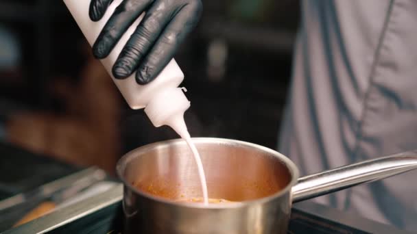 プロのレストランのキッチンシェフは スープにココナッツミルクを追加スパイシーなトムおいしいスープアジア料理をクローズアップ — ストック動画