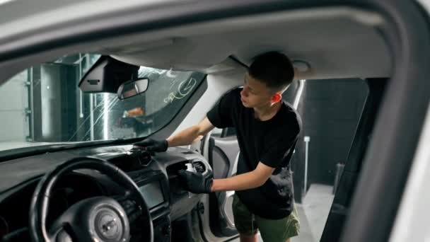 詳細なプロセス中に高級車のダッシュボードをきれいにするために ブラシと車の化学物質を使用して洗車労働者のクローズアップ — ストック動画