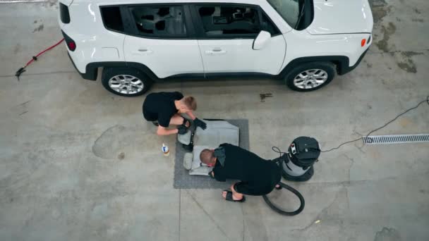 Mitarbeiter Einer Waschanlage Mit Einem Staubsauger Weiße Autositze Beim Entwirren — Stockvideo