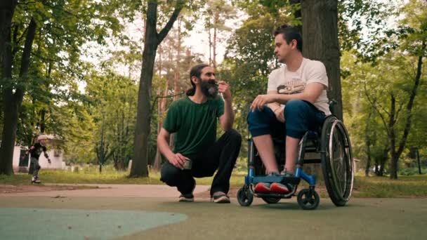 Seorang Pria Kursi Roda Beristirahat Dengan Seorang Teman Yang Merokok — Stok Video
