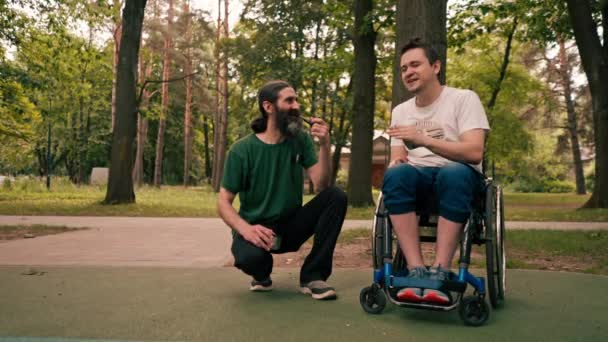 Человек Инвалидной Коляске Отдыхает Другом Который Курит Трубку Парке — стоковое видео