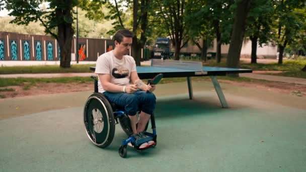 在比赛开始前 坐在轮椅上的年轻人看着网球拍 准备去公园参加比赛 — 图库视频影像