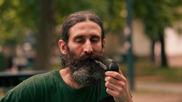 Portret Brodatego Dorosłego Mężczyzny Trzymającego Fajkę Tytoniem Parku Miejskim Wydychającego — Wideo stockowe