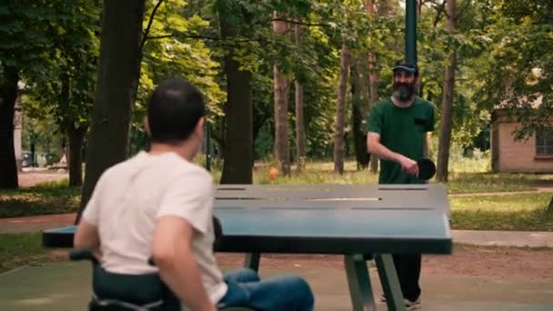 Hombre Silla Ruedas Juega Ping Pong Mesa Con Amigo Parque — Vídeos de Stock