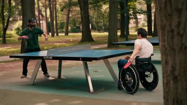 Ein Mann Rollstuhl Spielt Mit Seinem Freund Tischtennis Stadtpark — Stockvideo