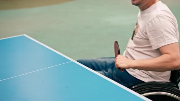 一位坐在轮椅上的男子在城市公园里打乒乓球 他在感情上是用乒乓球来练习射击的 — 图库视频影像