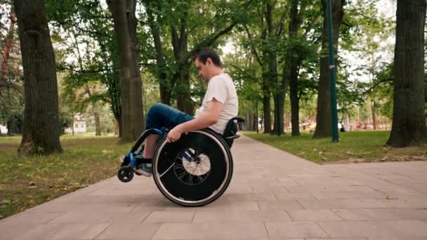 Χαμογελαστός Νεαρός Εκτελεί Κόλπα Μια Αναπηρική Καρέκλα Στο Πάρκο Της — Αρχείο Βίντεο