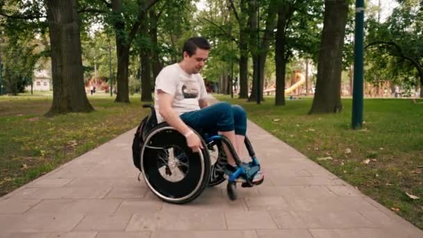 Uśmiechnięty Młody Człowiek Wykonuje Sztuczki Wózku Inwalidzkim Parku Miejskim Aktywny — Wideo stockowe