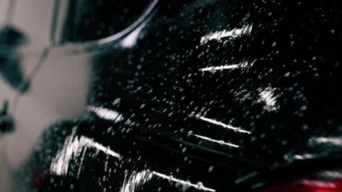 Oto yıkama deterjanı araba yıkarken veya araba yıkarken lüks bir arabadan damlıyor.