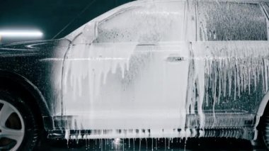 Oto yıkama deterjanı araba yıkarken veya araba yıkarken lüks bir arabadan damlıyor.